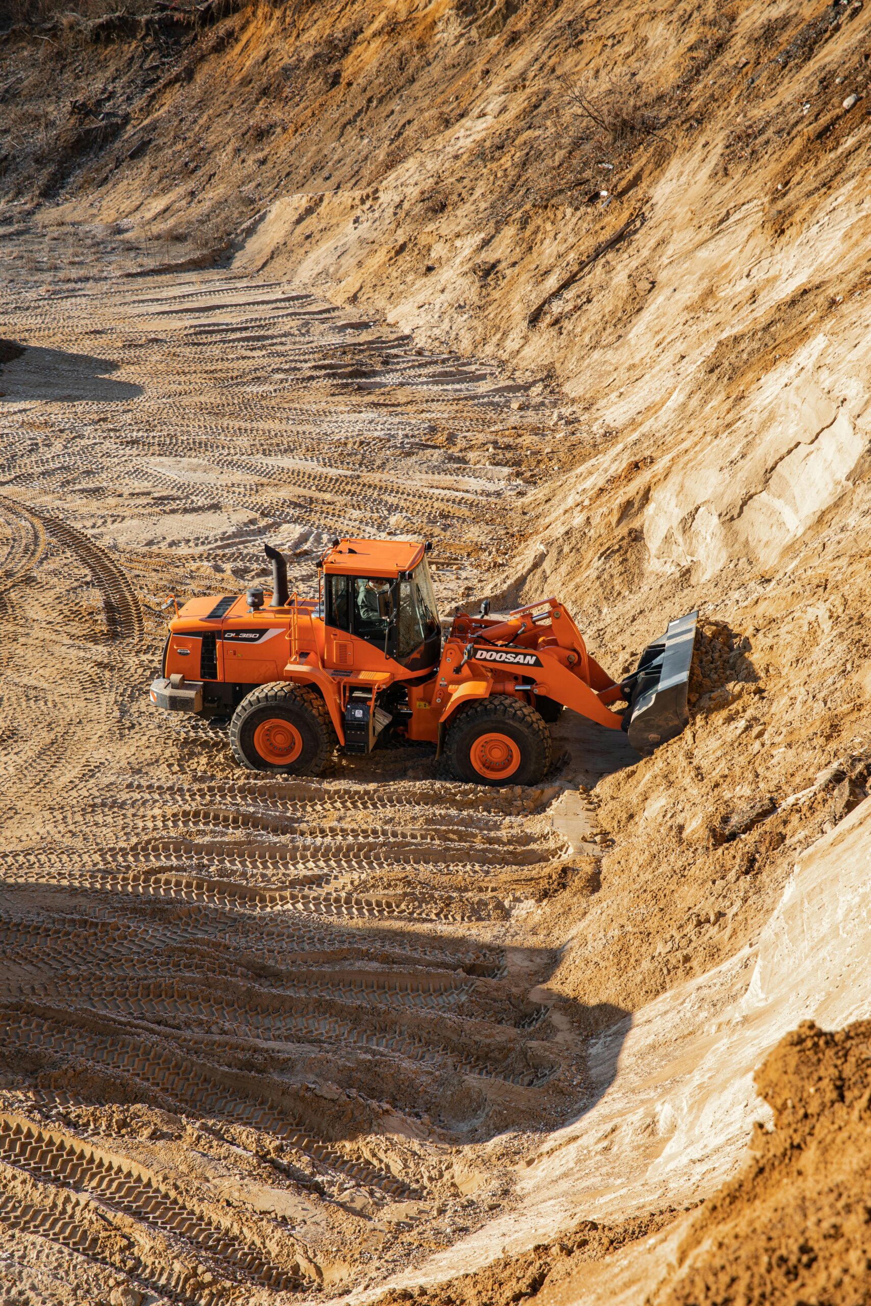 High-angle shot of an orange wheel loader working on a sandy construction site.