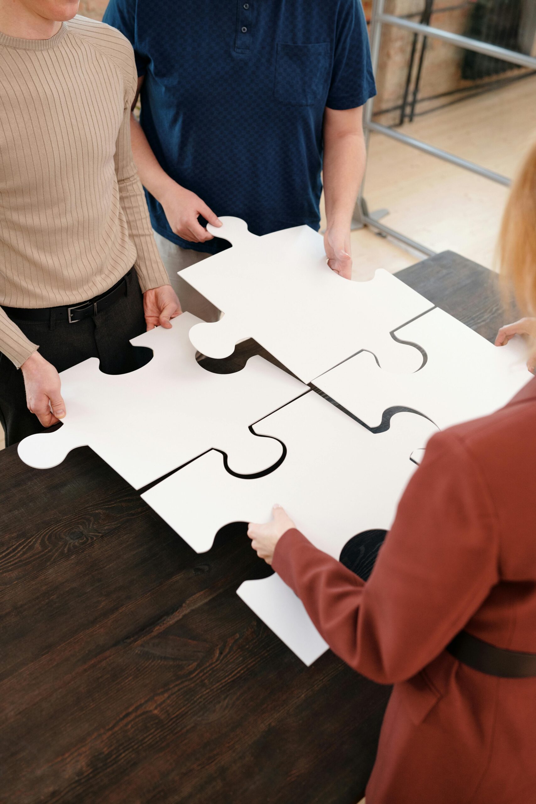 Team of adults working together on large puzzle pieces, symbolizing teamwork and unity.