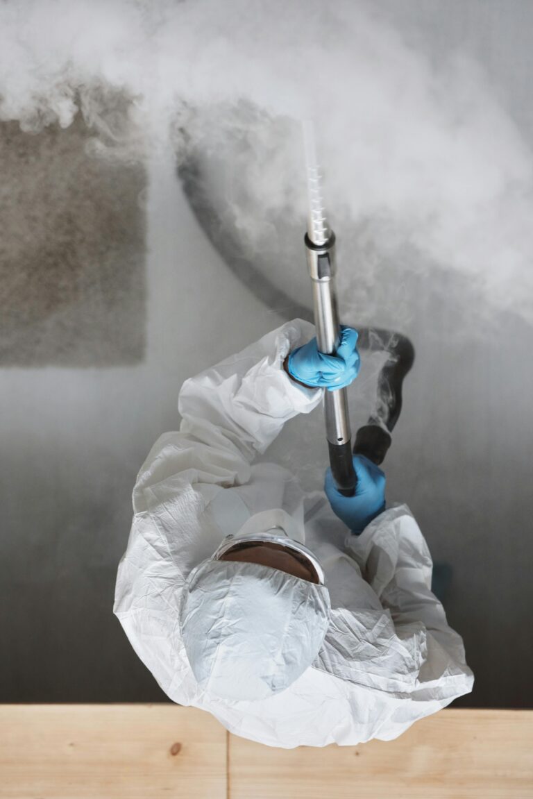 Man in protective suit sanitizes with a fogger from above.