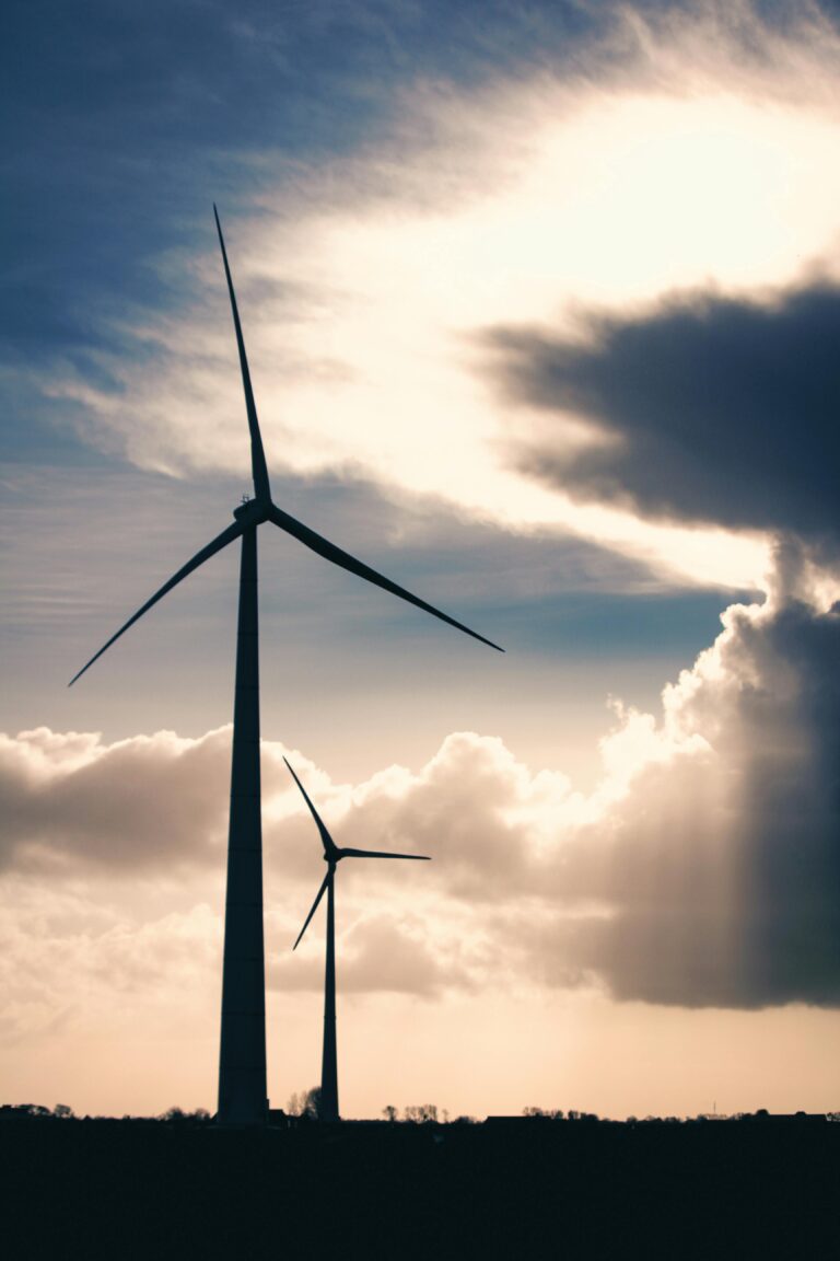 Silhouettes of wind turbines against a cloudy, dramatic sky demonstrating renewable energy.