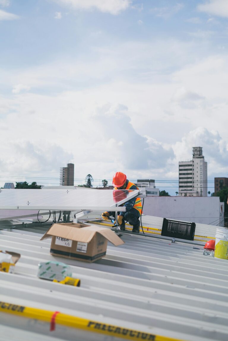 Solar technician working on rooftop installation of photovoltaic panels on a sunny day.